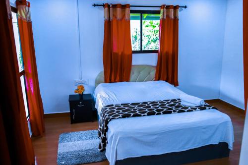 Schlafzimmer mit einem Bett mit orangefarbenen Vorhängen und einem Fenster in der Unterkunft ExoticaHolidays in Sultan Bathery