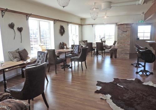 a restaurant with chairs and tables and a room with windows at Hotell & Spa Lögnäs Gård in Laholm