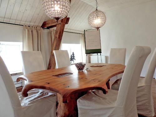 a dining room with a wooden table and white chairs at Hotell & Spa Lögnäs Gård in Laholm