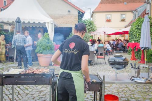a man cooking meat on a grill at an outdoor event at Der Patrizierhof - Weingut Gasthof Hotel - Familie Grebner in Großlangheim