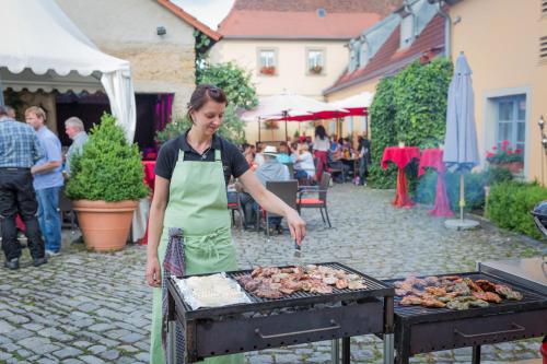 a woman in an apron cooking food on a grill at Der Patrizierhof - Weingut Gasthof Hotel - Familie Grebner in Großlangheim