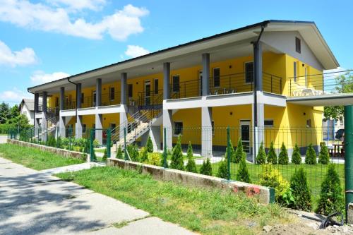 a yellow and white building with a fence around it at Promenád apartmány in Veľký Meder