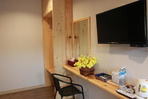 a room with a shelf with a television and a chair at Green Two Resort in Chanthaburi