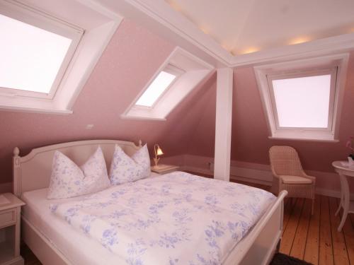 a bedroom with a white bed with two windows at Hotel Villa Caldera in Cuxhaven