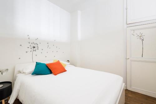 Una cama blanca con dos almohadas coloridas. en L'Atelier Nantais by Cocoonr, en Nantes