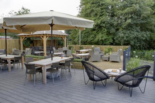a patio with tables and chairs and an umbrella at Best Western Plus Ullesthorpe Court Hotel & Golf Club in Lutterworth