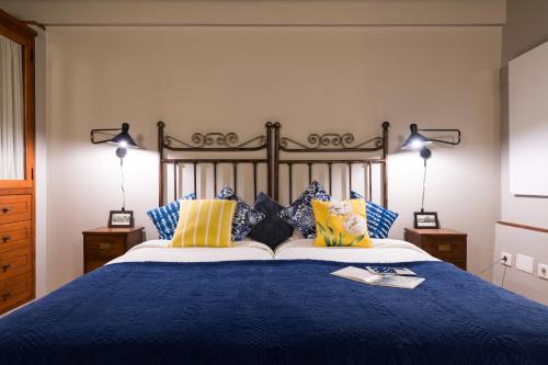 a bedroom with a blue bed with yellow and blue pillows at Bohemian Hideaway Finca - 2 unique houses with shared pool in Santa Lucía