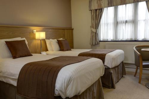 a hotel room with two beds and a window at Best Western Plus Ullesthorpe Court Hotel & Golf Club in Lutterworth