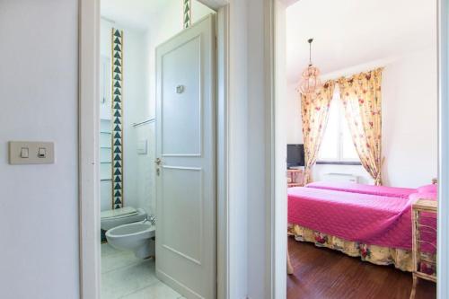 a bedroom with a pink bed and a bathroom at Villa Rita in Forte dei Marmi