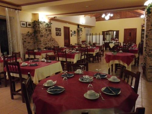 a restaurant with tables and chairs with red table cloth at La Casa del Filandón- HOTEL RURAL in Quintanilla de Somoza