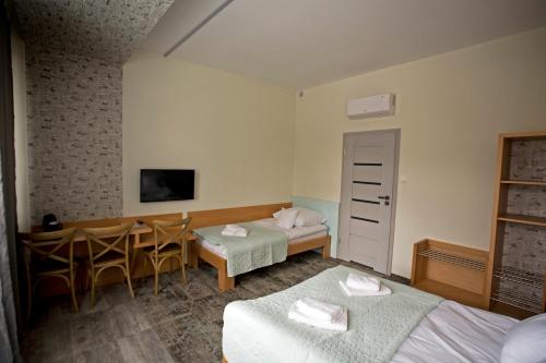 a hotel room with two beds and a table and chairs at Motelik Grosar Gorlice in Gorlice