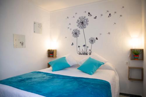 a bedroom with a bed with blue pillows and butterflies on the wall at La Casa Del Recreo in Cómpeta
