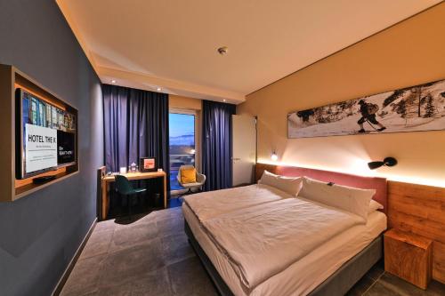 a bedroom with a bed and a desk and a television at BEST WESTERN Hotel The K Unterföhring in Munich