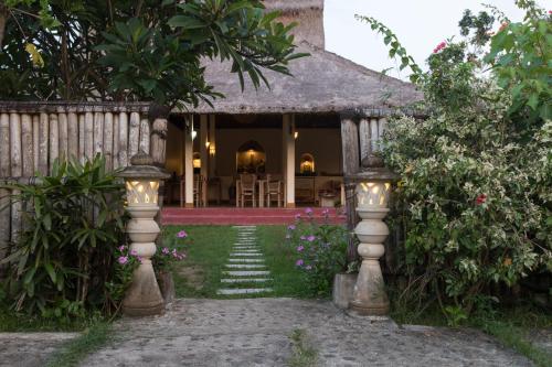 an entrance to a house with a garden with flowers at Owa Lodge Areguling in Kuta Lombok