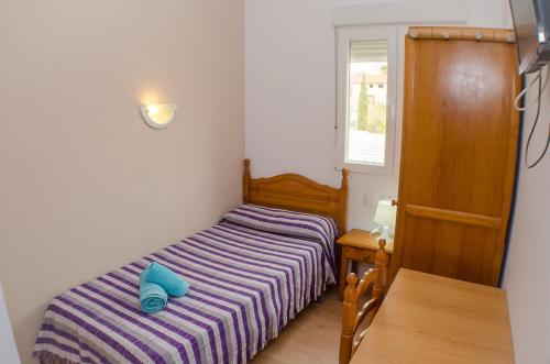 a small bedroom with a bed and a window at Hostal Los Calatravos in Alcañiz