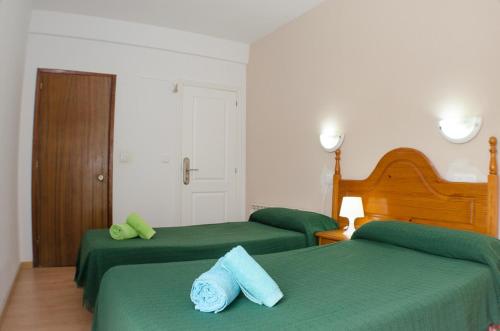 a bedroom with two green beds and a door at Hostal Los Calatravos in Alcañiz