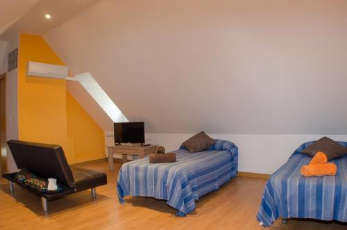 a room with two beds and a chair and a tv at Hostal Los Calatravos in Alcañiz