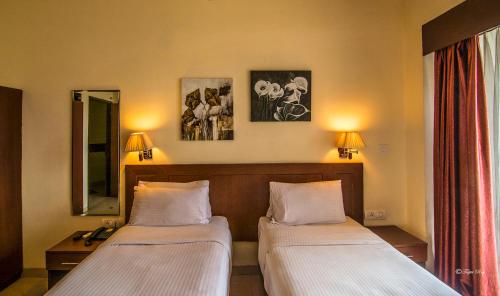Habitación de hotel con 2 camas y espejo en The Queeny en Vāsco Da Gāma