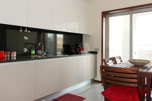 a kitchen with white cabinets and a table with a dining room at Apartamento Latino Coelho in Póvoa de Varzim