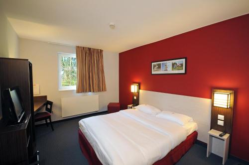 a hotel room with a bed and a red wall at DC Hotel Charleroi Airport in Charleroi