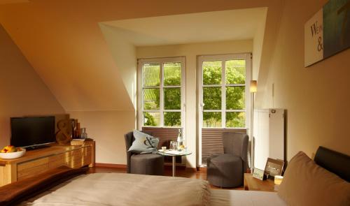 a bedroom with a bed and two chairs and a television at Wein- & Tafelhaus in Trittenheim