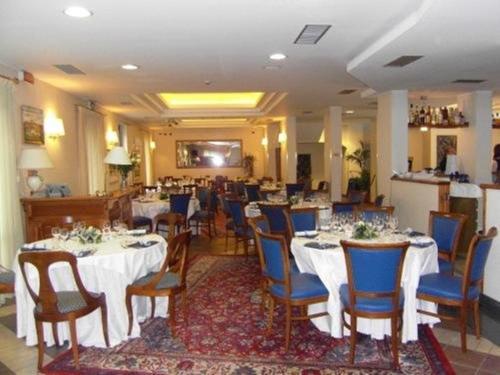 uma sala de jantar com mesas brancas e cadeiras azuis em Hotel Villa Savoia em Turim