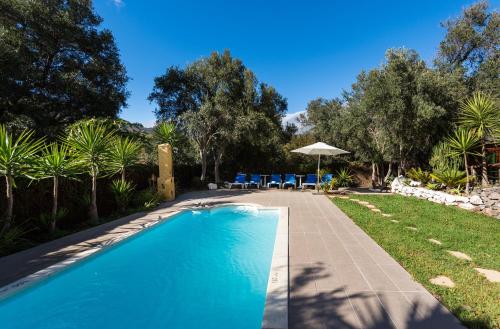 uma piscina num quintal com cadeiras e um guarda-sol em Bohemian Hideaway Finca - 2 unique houses with shared pool em Santa Lucía