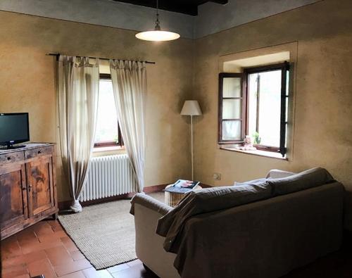 salon z kanapą i dwoma oknami w obiekcie Agriturismo La Costa - Casa Vacanze w mieście Perego