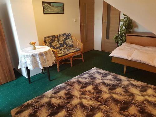 a room with a bed and a chair and a table at Apart-Bungalovy Gitka in Mlynčeky