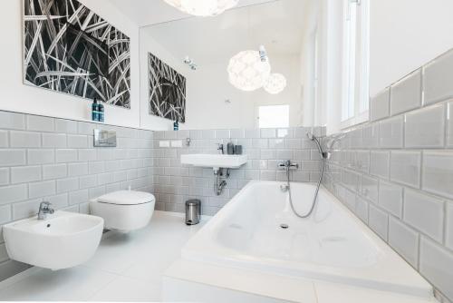 a bathroom with a tub and a toilet and a sink at Penthouse Skyline by LoftAffair in Krakow