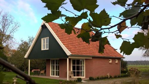 a red house with a black roof at Villa Smalspoor in Markelo