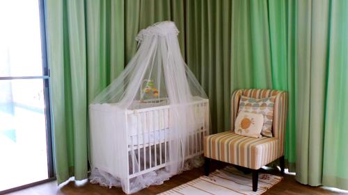 a crib with a canopy and a chair in a room at Villa Baan Saitara in Lamai
