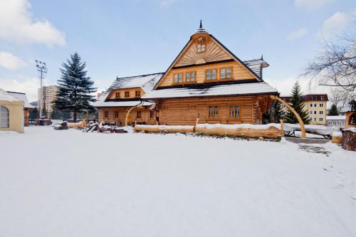 a large wooden house with snow on the ground at Penzión Koliba in Dolný Kubín