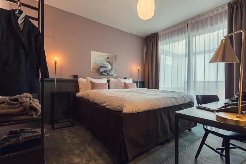 a hotel room with a bed and a desk and a window at Best Western Plus Hus 57 in Ängelholm
