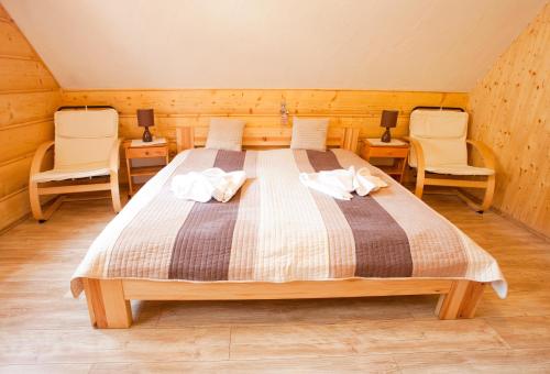 a bedroom with a large bed with two chairs at Penzión Koliba in Dolný Kubín