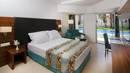 a hotel room with a bed and a chair at Palm Wings Kusadasi Beach Resort&Spa in Davutlar