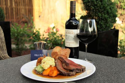 a plate of meat and vegetables with a glass of wine at Belgrave Sands Hotel & Spa in Torquay