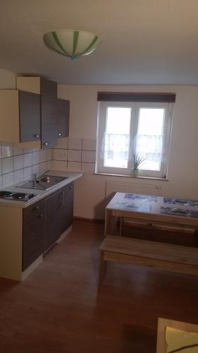 a kitchen with a sink and a table and two windows at Ferienwohnung Kieble in Ichenhausen