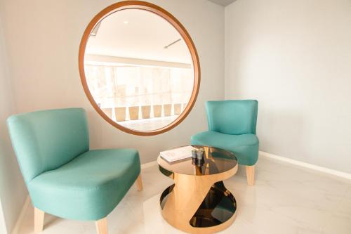two chairs and a table in a room with a mirror at Hotel MAYU Chiang Mai in Chiang Mai