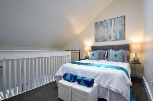 a bedroom with a large white bed with blue pillows at Modern Loft wQueen Loft Steps to Beach in Hollywood