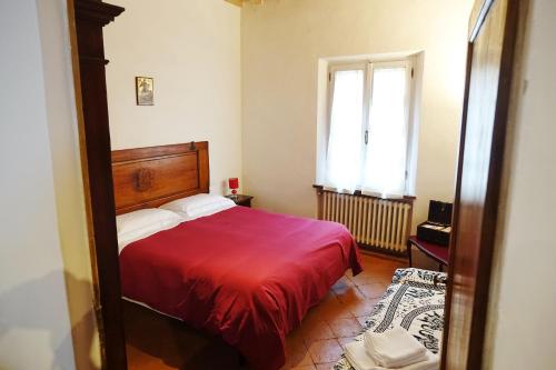 モンテプルチャーノにあるPalazzo Colombiのベッドルーム1室(赤いベッド1台、窓付)