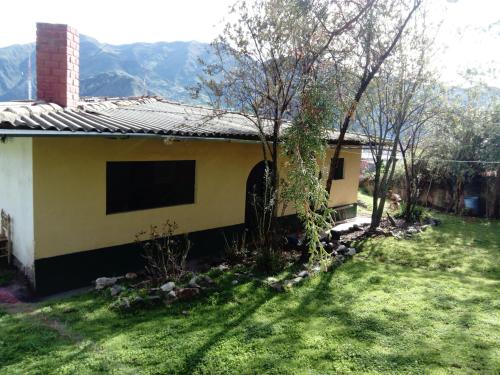 una pequeña casa en un patio con montañas al fondo en Nilo Trek House, en Chiquián