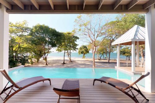 a view of a swimming pool from the deck of a house at Updated Beachfront Paradise Infinity Pool Roatan in Palmetto Bay