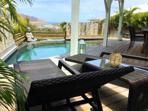 a patio with a table and chairs next to a pool at Villa La Voile Blanche in Orient Bay