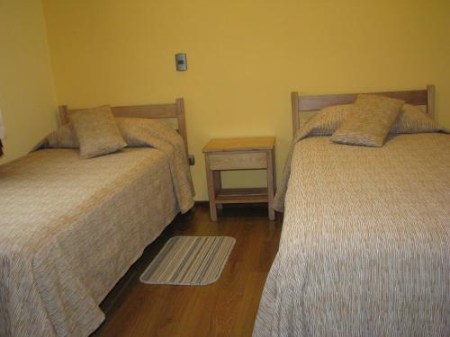 two beds in a room with a nightstand between them at Portal Austral in Puerto Montt
