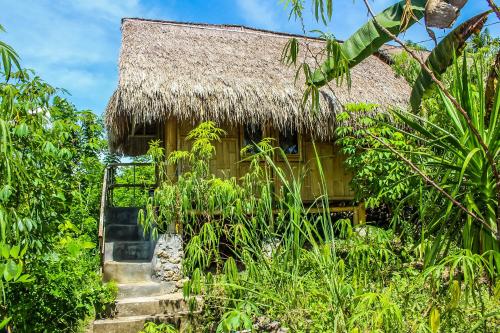 ペニダ島にあるEcho Alam Nusa Lodgeのジャングル内茅葺き屋根の家