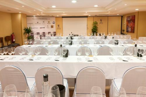 a large room with white tables and chairs with wine glasses at Hotel Gran Via in Logroño