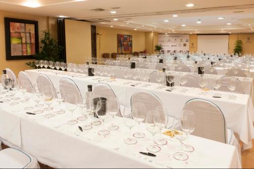 a large room with white tables and chairs with wine glasses at Hotel Gran Via in Logroño