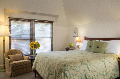 a bedroom with a bed and a chair and a window at Cheshire Cat Inn & Cottages in Santa Barbara
