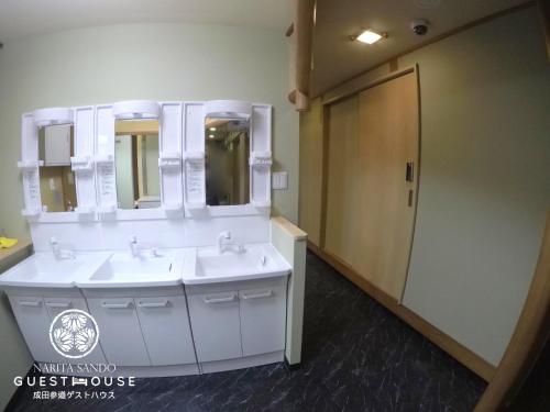 a bathroom with two sinks and a large mirror at Narita Sando Guesthouse in Narita